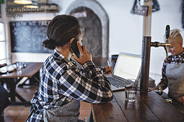 Managerin beim Telefonieren mit dem Laptop an der Theke