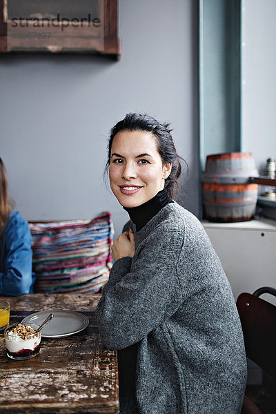 Porträt einer lächelnden Frau beim Brunch am Tisch