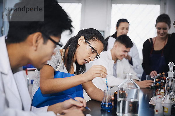 Junge multiethnische Studenten beim Mischen von Lösungen im Chemielabor