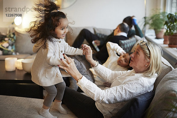 Mädchen spielt mit Großmutter auf dem Sofa von der Familie zu Hause