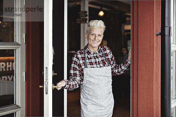 Porträt eines lächelnden  selbstbewussten Handwerkers am Eingang des Restaurants