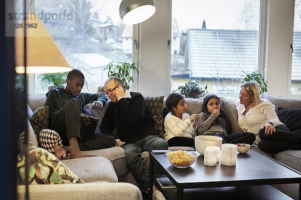 Mehrgenerationen-Familie sitzt zu Hause auf dem Sofa