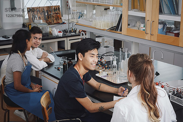 Hochwinkelansicht von multiethnischen jungen Universitätsstudenten  die auf Stühlen im Chemielabor sitzen.