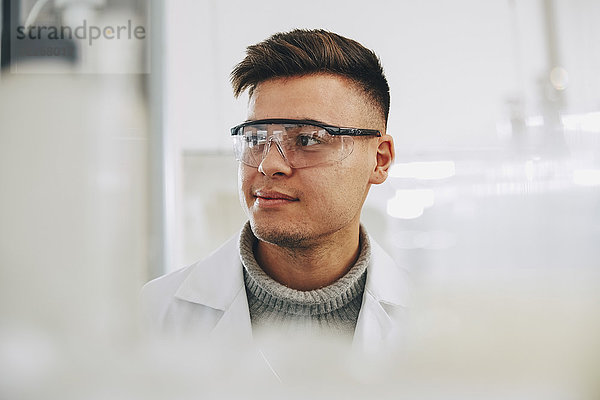 Zuversichtlicher junger Chemiestudent mit Brille im Labor