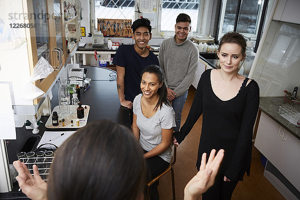 Hochwinkelansicht einer Lehrerin  die glücklichen multiethnischen Schülern im Chemielabor erklärt.