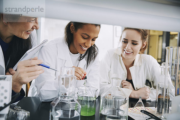 Lächelnde multiethnische Universitätsstudenten mit ausgereifter Lehrer-Mischlösung im Labor