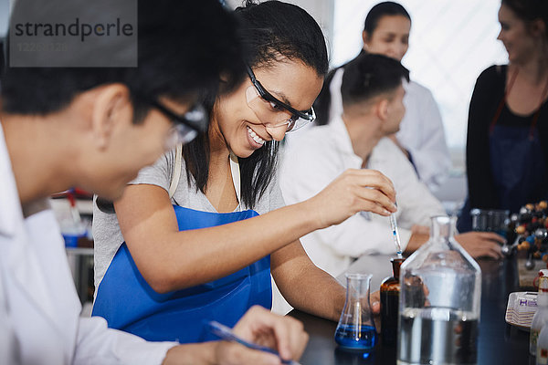 Lächelnde multiethnische Studenten beim Mischen von Lösungen im Chemielabor