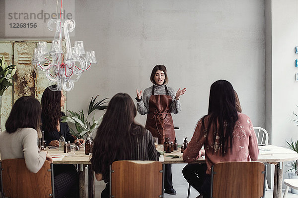Selbstbewusste Unternehmerin erklärt den Kollegen am Tisch in der Parfumwerkstatt