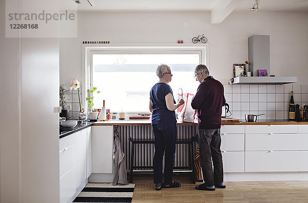 Durchgehende Rückansicht des pensionierten Seniorenpaares in der heimischen Küche