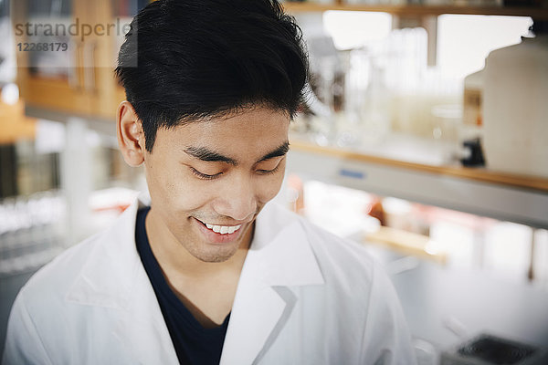 Lächelnder junger männlicher Student schaut auf das Chemielabor herab