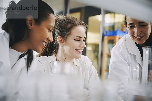 Glückliche  reife Lehrerin mit jungen  multiethnischen Studentinnen  die im Chemielabor lernen.