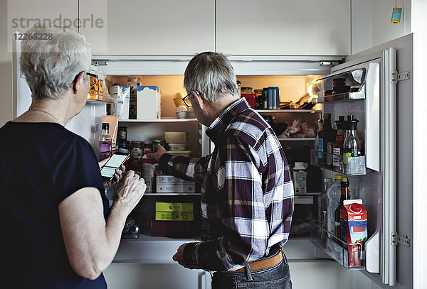 Seniorenpaar steht neben Kühlschrank in der Küche zu Hause