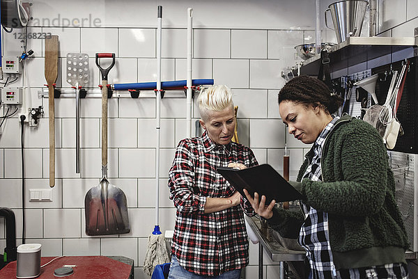 Arbeitnehmerinnen diskutieren in der Brauerei über digitale Tabletten