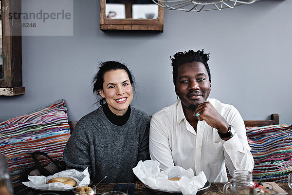 Porträt von lächelnden multiethnischen Freunden am Esstisch im Restaurant