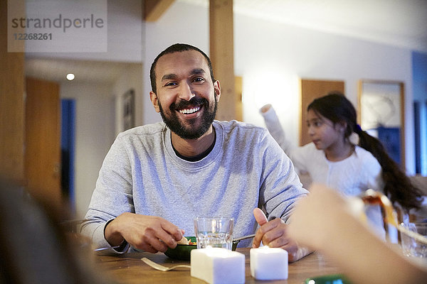 Lächelnder Mann beim Essen mit der Familie zu Hause