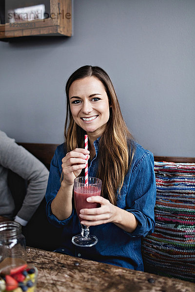Porträt eines lächelnden jungen Kunden beim Trinken am Esstisch im Restaurant