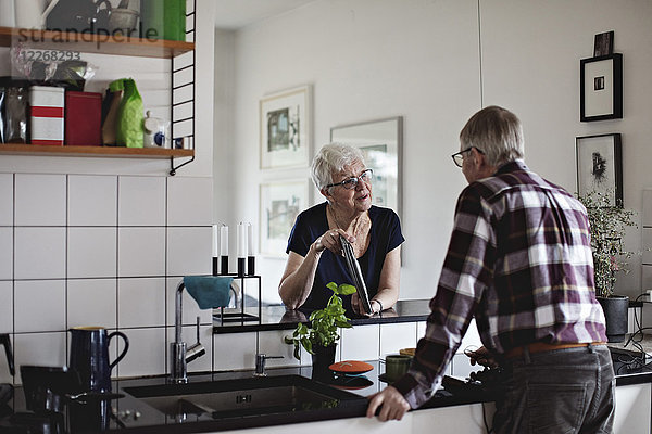 Senioren-Paar im Ruhestand am Küchentisch bei der Diskussion über digitale Tabletten