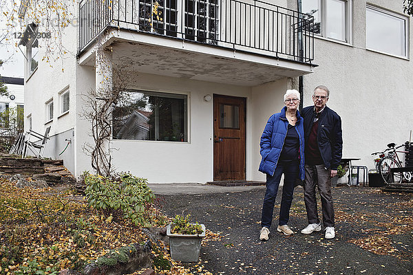Porträt eines pensionierten Seniorenpaares  das gegen das Haus steht.