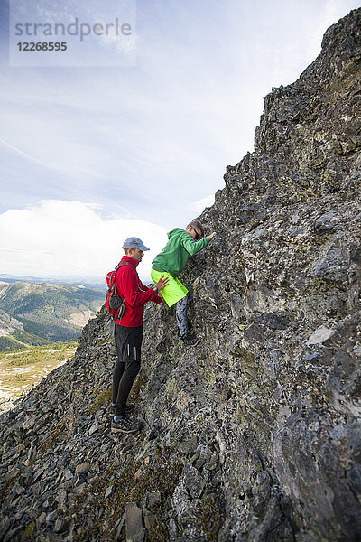 Vater führt Sohn auf steilem Kletterabschnitt einer Wanderroute  Merritt  British Columbia  Kanada