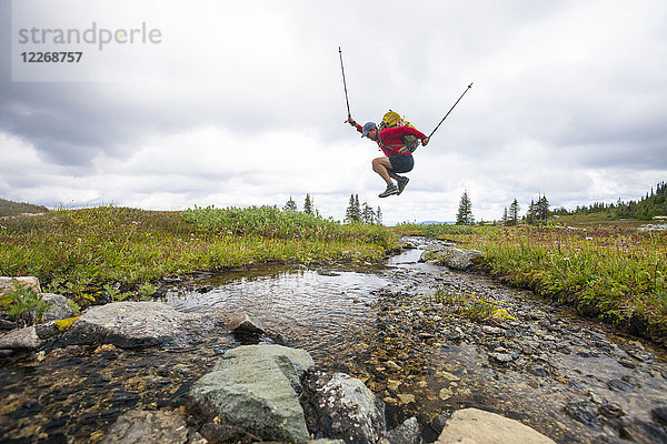 Seitenansicht eines Mannes  der über einen kleinen Bach springt  Merritt  British Columbia  Kanada