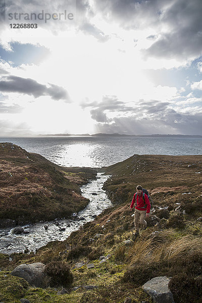 Rucksacktourist beim Wandern entlang eines Baches an der Küste  Torridon  Schottland  UK