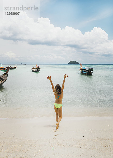 Junge Frau im Bikini  die mit erhobenen Armen am Strand Richtung Meer läuft  Tambon Ko Tarutao  Chang Wat Satun  Thailand