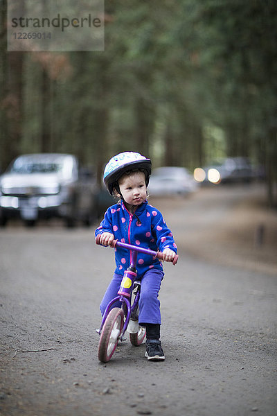 Mädchen fährt mit einem Kinderfahrrad auf einer Straße im Wald  Harrison Hot Springs  British Columbia  Kanada