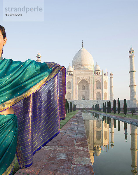 Rückansicht einer Sari tragenden Frau am Taj Mahal-Palast und Mausoleum  einem UNESCO-Weltkulturerbe  einem Palast mit weißen Marmorwänden  in die dekorative Details eingelegt sind.