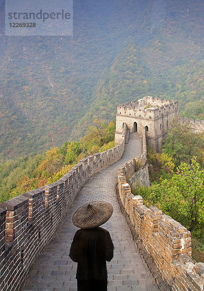 Rückansicht eines Mannes mit traditionellem Strohhut auf der Großen Mauer von China.