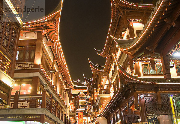 Niedrigwinkelansicht von beleuchteten traditionellen orientalischen Gebäuden mit Balkonen bei Nacht.