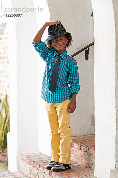 Porträt eines Jungen  der im Freien steht und einen Filzhut trägt