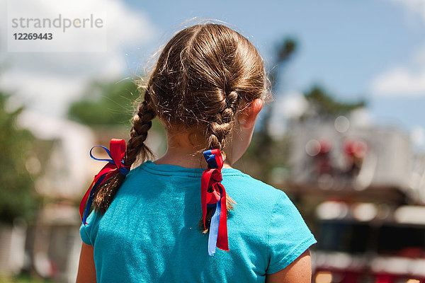 Mädchen mit geflochtenem Haar  rote und blaue Bänder im Haar  Rückenansicht