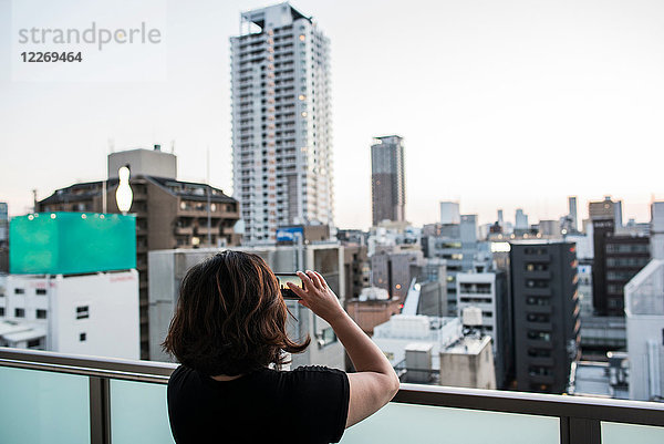 Frau fotografiert Sonnenuntergang vom Balkon aus  Osaka  Japan