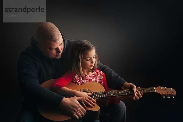 Vater lehrt Tochter Gitarre spielen