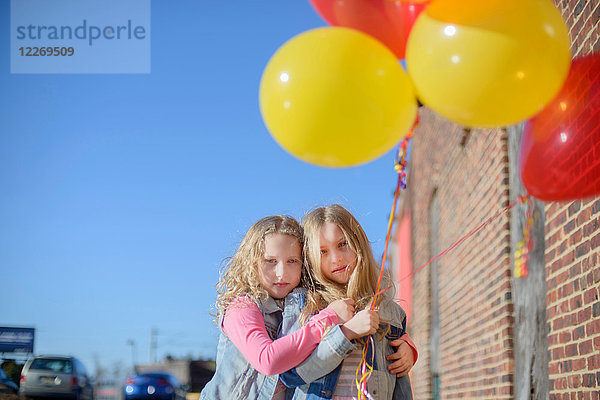Zwei Schwestern mit einem Haufen bunter Luftballons  Porträt