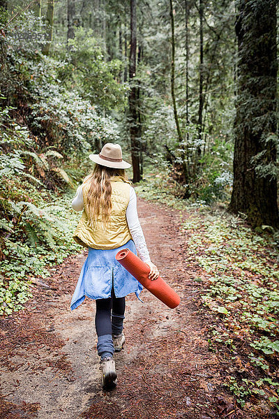 Junge Frau im Trilby beim Waldspaziergang  Rückansicht