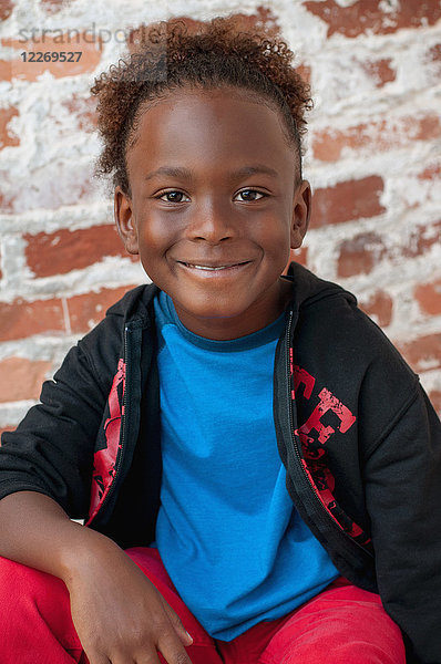 Porträt eines Jungen  der im Freien sitzt und lächelt