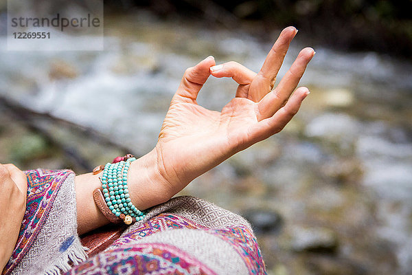 Junge Frau meditiert am Fluss  Nahaufnahme der Hand