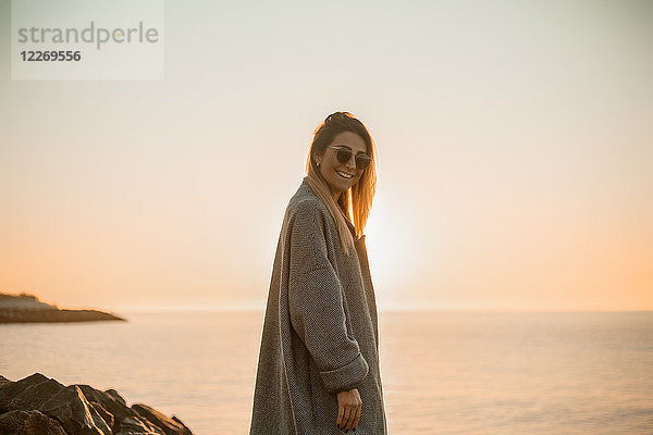 Porträt einer Frau mit Sonnenbrille und Wintermantel  die lächelnd in die Kamera blickt  Seitenansicht  Odessa  Odeska Oblast  Ukraine  Osteuropa