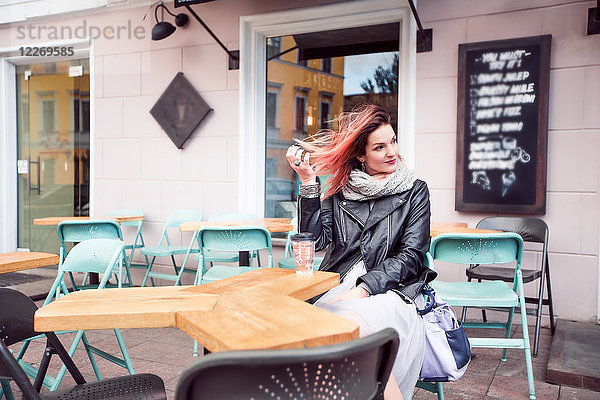 Frau sitzt am Tisch im Straßencafé