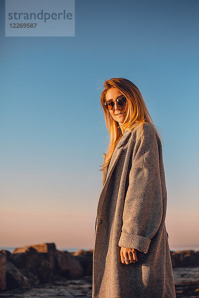 Porträt einer Frau mit Sonnenbrille und Wintermantel  die lächelnd in die Kamera blickt  Seitenansicht  Odessa  Odeska Oblast  Ukraine  Osteuropa