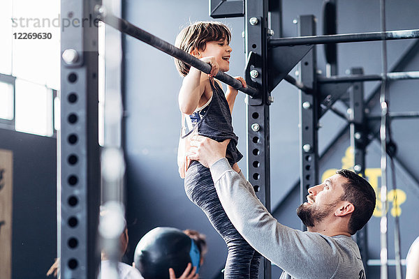 Vater und Tochter benutzen Klimmzugstange im Fitnessstudio