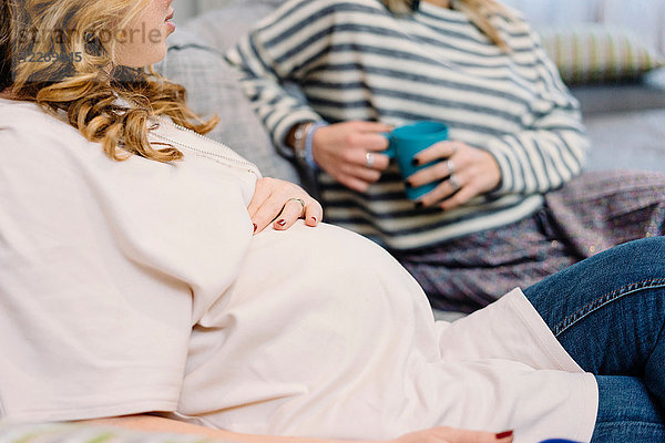 Schwangere und Freundin auf Sofa  beschnitten