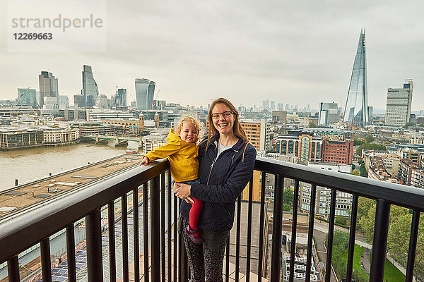 Frau und Kleinkindtochter auf Balkon mit Londoner Skyline  Porträt