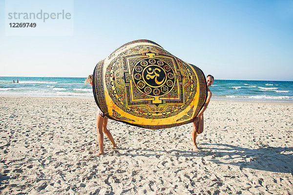 Ausgewachsenes Paar im Freien  das eine Stranddecke zwischen sich hält