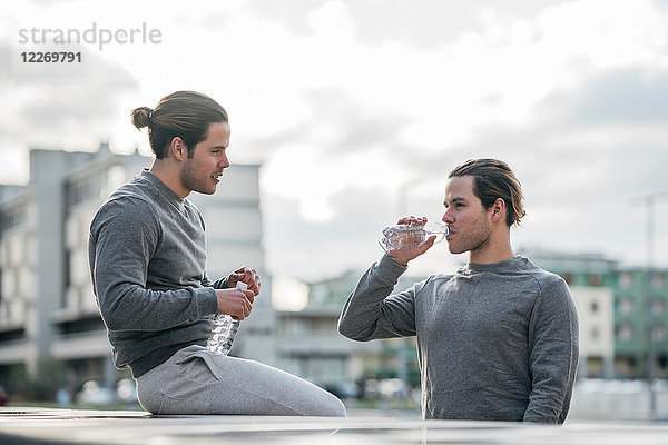 Junge erwachsene männliche Zwillinge machen eine Trainingspause  Trinkwasser