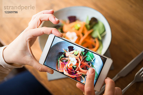 Frau fotografiert veganes Essen