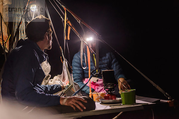 Zwei Bergsteiger sitzen nachts auf der Portalege  Liming  Provinz Yunnan  China