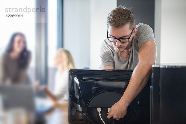 Computertechniker  der Kabel an einen Computer im Büro anschließt