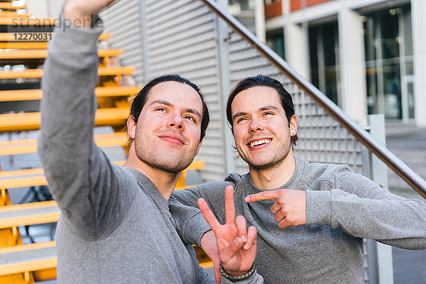Junge erwachsene männliche Zwillinge trainieren zusammen und machen ein Selbstporträt